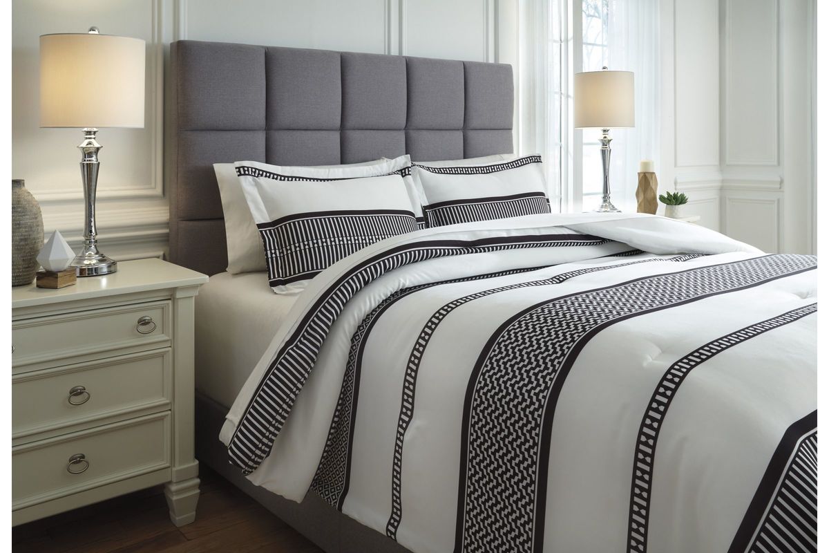 Queen bed with white comforter set and striking black geometric pattern details